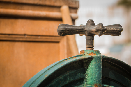 Old rusty faucet painted in green color on the wooden background in sunny day, horizontalの写真素材