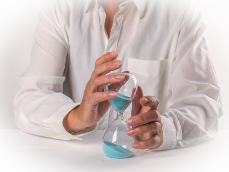 Woman holds carefully a hourglass, of watching the runaway sand in an hourglass. Concept. Half life...