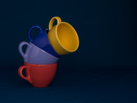 Four some cups of coffee of  different  vibrant colors in on the dark blue background.の写真素材