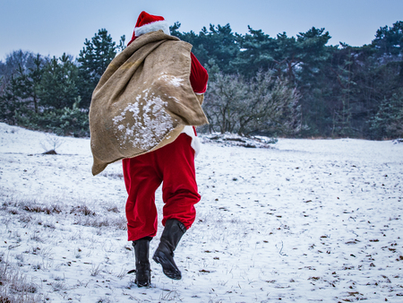 Santa Claus coming to the winter forest with a bag of gifts, snow landscape,の写真素材