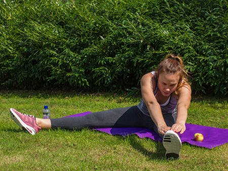 Young woman fit busy with stretching exercises in nature outdoor