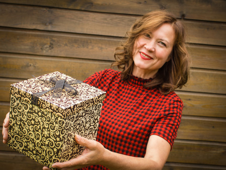 Brunette with a gift box with bow on the wooden background.