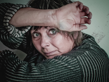 Fearful women of middle age hopelessly closed her face with her hands.の写真素材