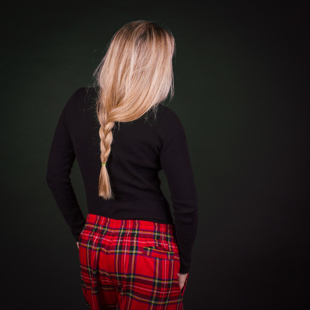 Thin blonde with a scythe hairstyle, rear view, studio shot on a dark green backgroundの写真素材