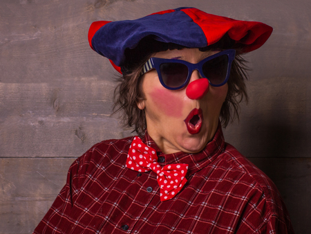 Comedian clown with a  blue-red big beret, big red nose and blue sunglasses.の写真素材