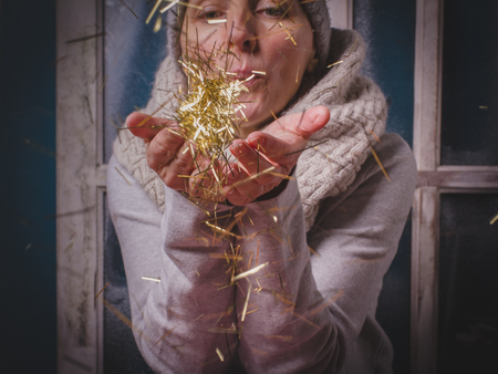 Golden sparkles in hands of woman close-up, hands in focus, model blurred. Cute female blond model...