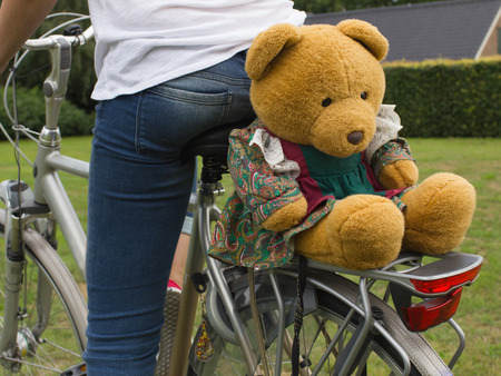 Fit woman butt on bike with big teddy bear, back view, close up.の写真素材