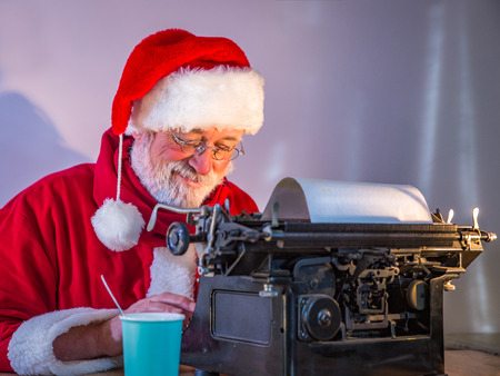 Portrait of happy Santa Claus sitting at his room at home responding to children's letters, close-up, insideの写真素材
