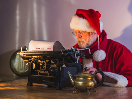 Santa Claus writing a message for people on old typewriter. Santa Claus out of focus, blurry.の写真素材