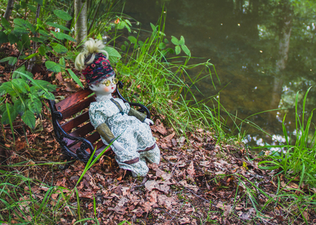 pathetic old doll sitting in a park, a state of povertyの写真素材
