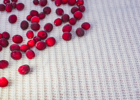Knitted white background and dark red frozen berries on top of image