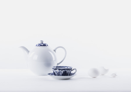 White still life with white teapot, white eggs on a white background and traditional cup of tea with china blue ornamentの写真素材
