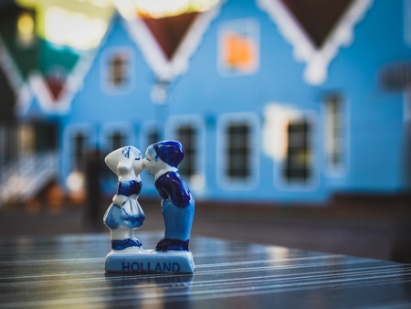 Valentine's day in Netherlands, blurred background of blue houses in the evening light with a traditional Dutch souvenir, a kiss for a boy and a girl close-upの写真素材