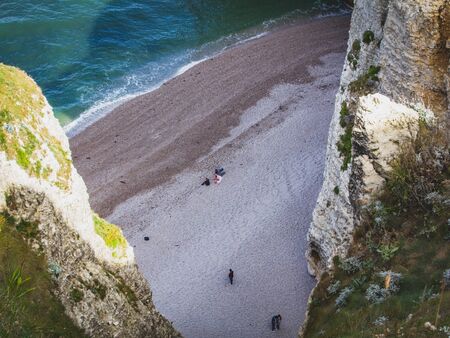 Magnificent top view of a small beach and sea water, holidaymakers people sitting on the beach, the Normandy coast, in northern France.の写真素材