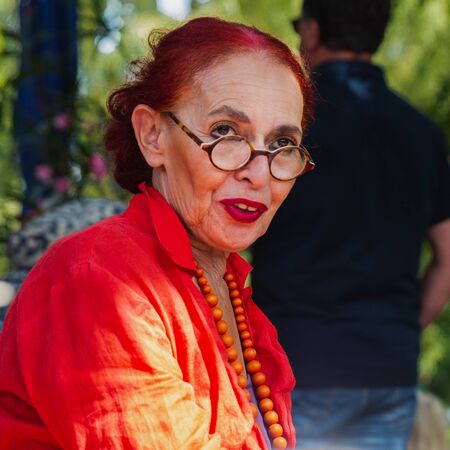 Portrait of extraordinary modern senior woman with red hair and linen dress outdoor, close-up.の写真素材