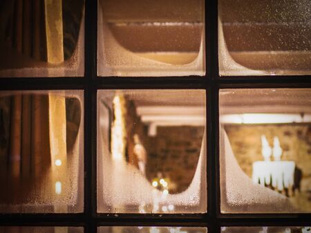 Christmas background, a window or part of a window, candles, baubles, balls and shiny golden lights on the windowsill, festive winter evening.Blur, festive atmosphere of Christmas night.の写真素材
