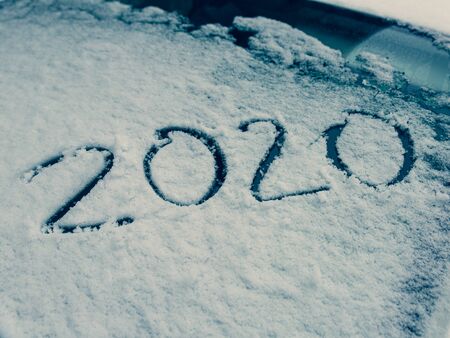 Snow on the  car where the numbers are written 2020, close-up window of the car. Top view,...