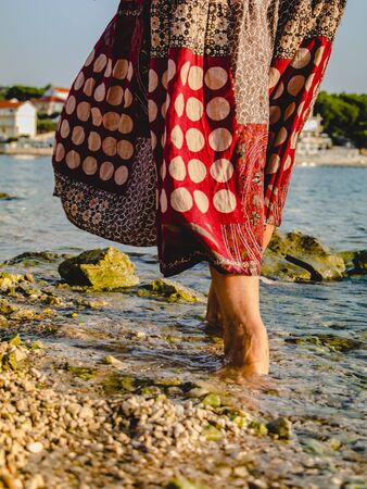 Female bare feet standing on the wet stones of the sea coast, close up.の写真素材