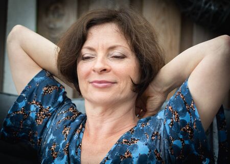 A bored and dreaming woman of retirement age sitting in garden.の写真素材