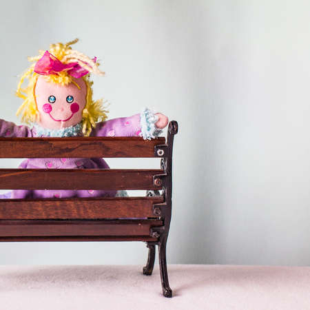 Unusual funny playful girl, a doll sitting on a bench.の写真素材