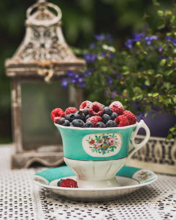 Fresh ripe, tasty, sweet raspberries and blueberries in a French porcelain bowl. Blurred background, selective focus.の写真素材