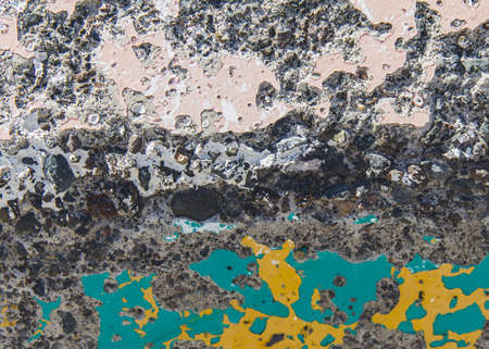 Grungy concrete wall background texture with damaged layers of stucco and pink, blue and yellow...