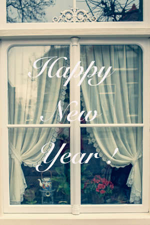 White window of ahouse with happy new year greeting text. Family and cozy life concept.