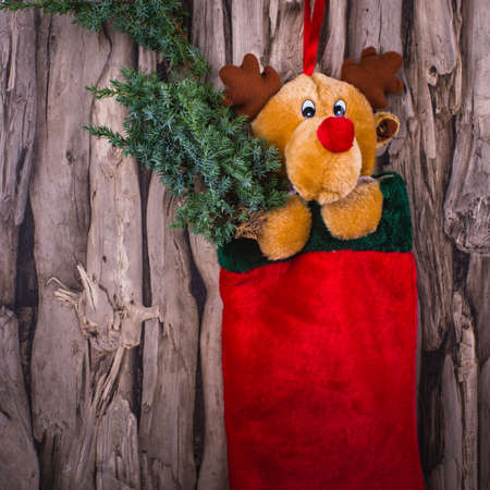 decorative toy with a traditional red bag of gifts on a rough wooden background.