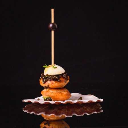 Black caviar with quail eggs, poffertjes, alfalfa, rucola over black background with copy space.の写真素材