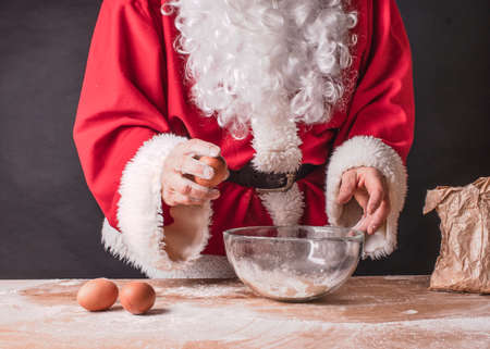 Santa Claus hands break an egg into flour.の写真素材