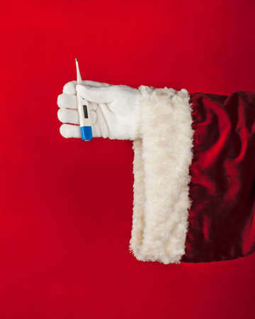 Close-up hand of Santa Claus holding in hands thermometer isolated on bright color background with copy space.の写真素材