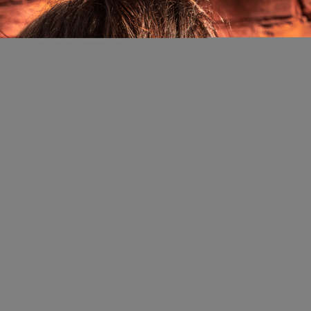 Close-up portrait of mature brunette against a warm tone brick wall background.の写真素材