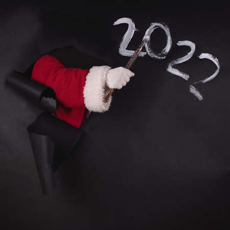 Santa Claus writes the numbers 2022 on a black paper