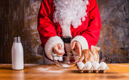 Festive simple cooking. Santa Claus is preparing food. Milk bottle, glass bowl, paper bag and eggs standing on the table.の写真素材