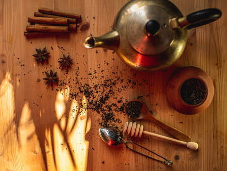 View of a table with an old bronze teapot, a ceramic teapot with tea and other tea accessories. Contrast of light and shadow, selective focus.の写真素材
