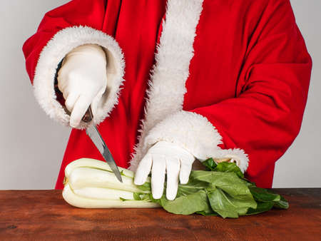 Santa Claus prepares a festive dish from fresh bok-choy. Healthy food concept.の写真素材
