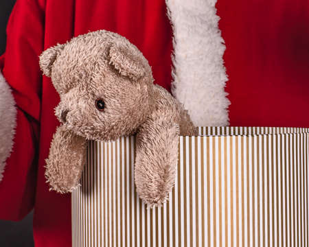 Santa Claus holds soft-toy, brown teddy bear in hand on black background with copy spaceの写真素材