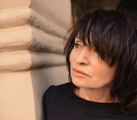 65 year old attractive brunette dreamily looking into the distance.