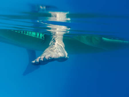 Detail of kid feet on a swimming pool. Family travel lifestyle, kids water sports activity on summer...