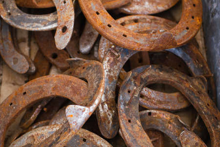 The horseshoes which were in the use lie in a thick layer. Abstract background of textured rusty metal, lot of used horseshoes.の写真素材