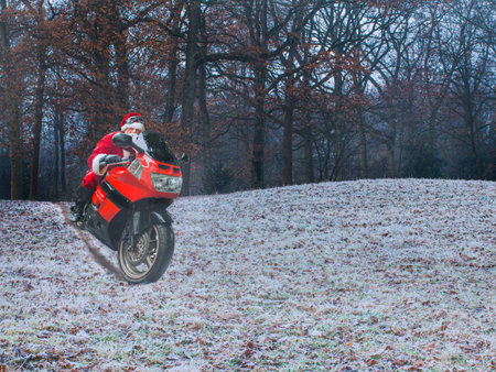 Christmas evening. Santa Claus on a red motorcycle quickly rides through the winter forest. The concept of a healthy and modern lifestyle. Place for text.の写真素材