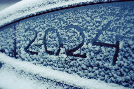 close-up snow-covered car window, numbers are written 2024, textured snowy backgroundの写真素材