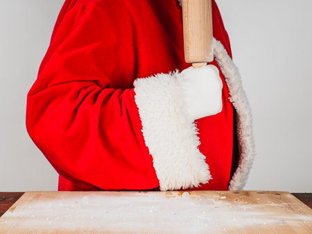 Close-up  Santa Claus in traditional costume holds a rolling pin. He is ready to start cooking a hundred pounds of flour.の写真素材