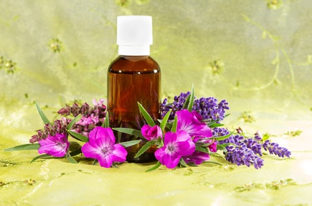 Brown glass bottle of essential oil plant extracts with fresh flowers of lavender and sidalcea, or prairie mallow, for use in aromatherapy and as a spa massage oilの写真素材