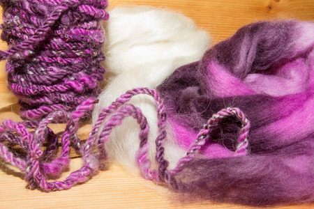 Close up of handspun artyarn on a spindle and a colorful wool fleece for artists.