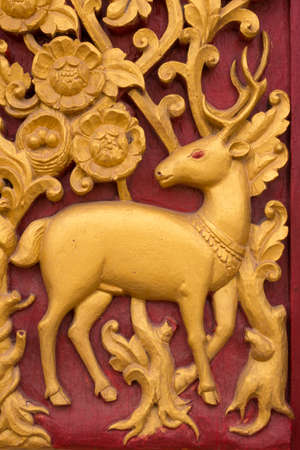 golden deer wooden sculpture  on the  door of Thai templeの写真素材