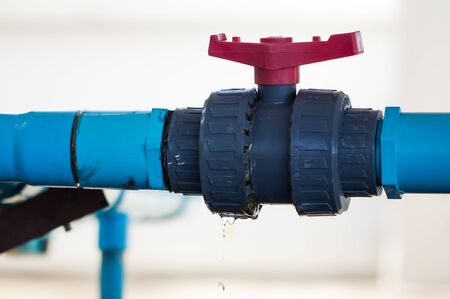 leaking water from blue pipe and red valveの写真素材