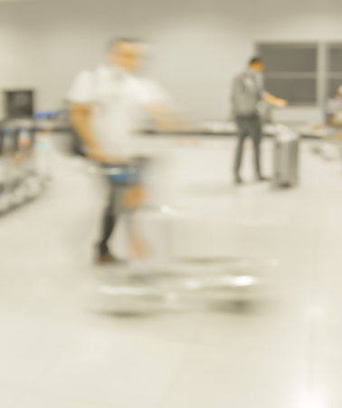 blur motion of walking people and trolley in airportの写真素材