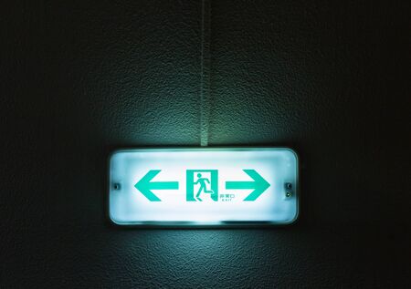 emergency green  fire exit sign on wall with black backgroundの写真素材