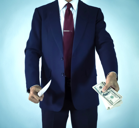 betray business man holding knife and moneyの写真素材